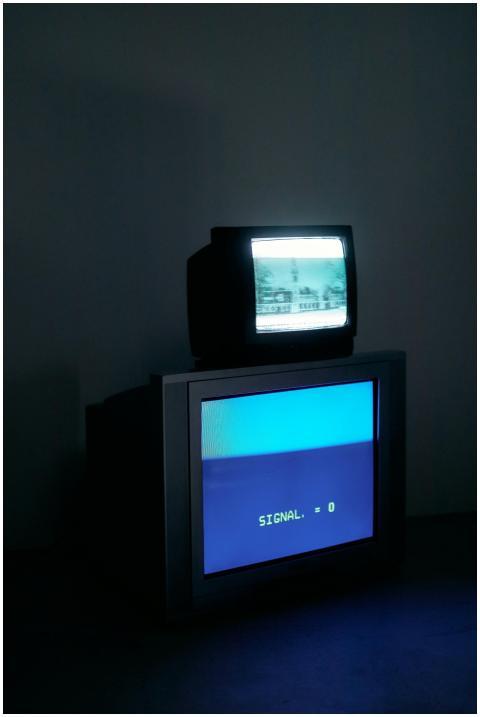 Two retro CRT monitors in a dark room showing 'SIG