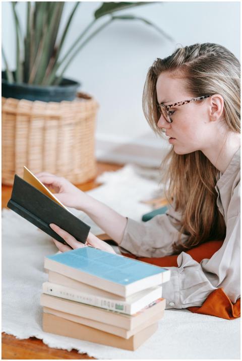 A young woman in glasses reads attentively next to