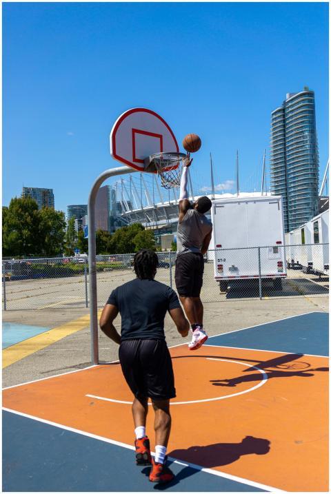 Two men playing basketball outdoors on a sunny day