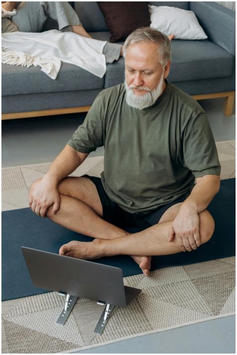Older man practicing yoga while following an onlin