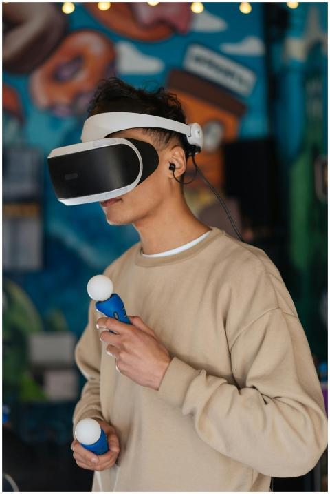 A young man wearing VR goggles and holding control