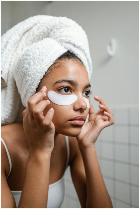 Young woman with a towel applies under eye masks d