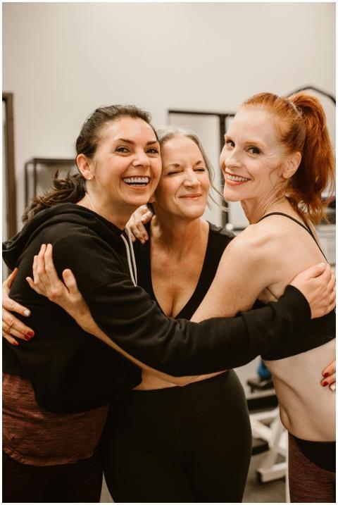 Three happy women hugging at the gym, celebrating