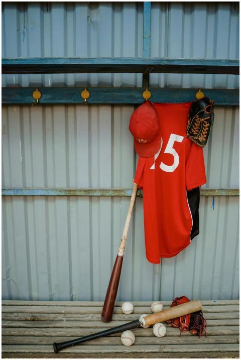 Red jersey and baseball gear hanging in dugout awa
