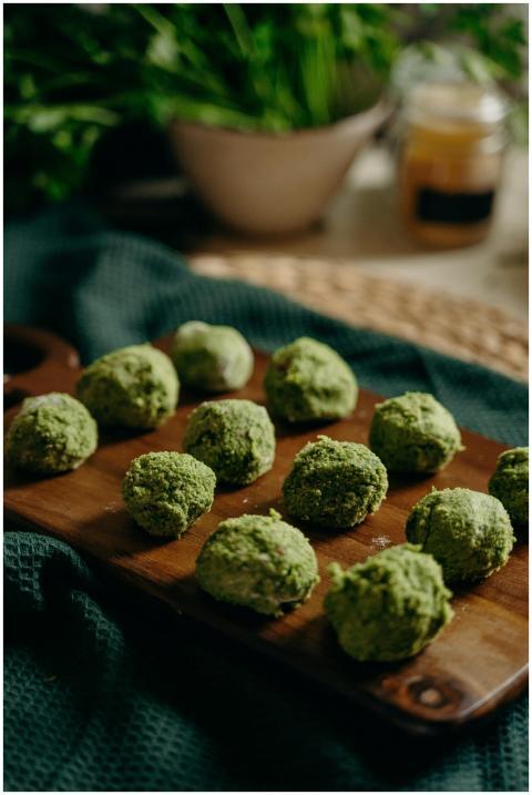 Freshly prepared green herb falafel on a wooden bo