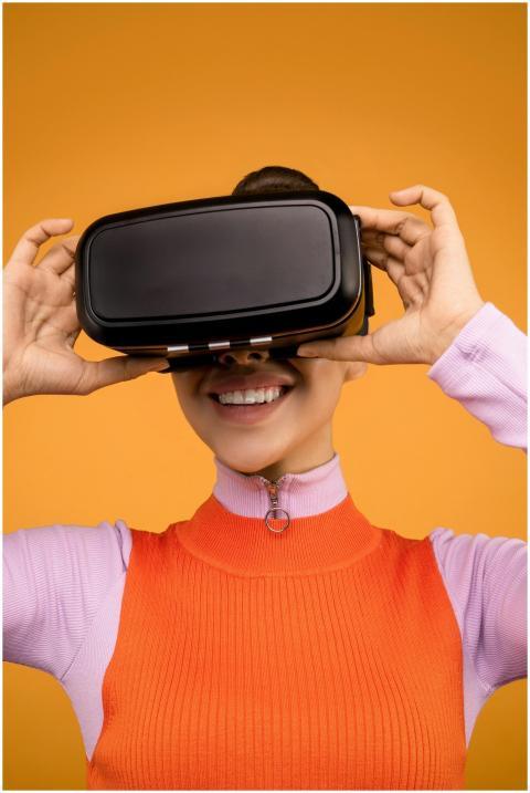 Smiling woman wearing VR headset on vibrant orange