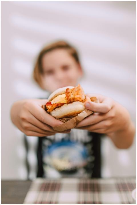 Blurred young person holding a fried chicken sandw