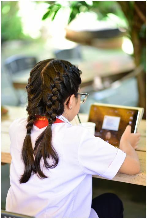 Back view of a young girl with braids using a tabl
