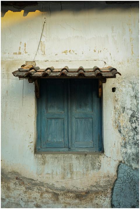A rustic blue wooden window on a weathered wall in