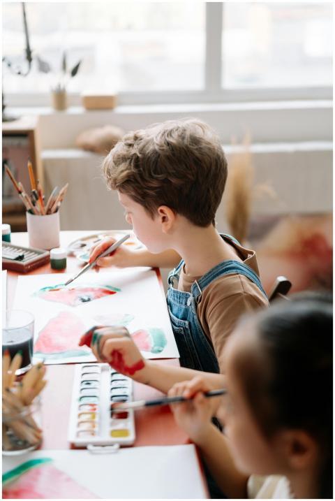 Children painting with watercolors in a sunny, ind