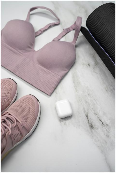 Pastel pink sports bra, sneakers, and yoga mat wit