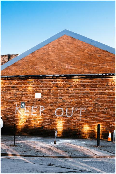 A brick warehouse wall with a 'Keep Out' sign, ill