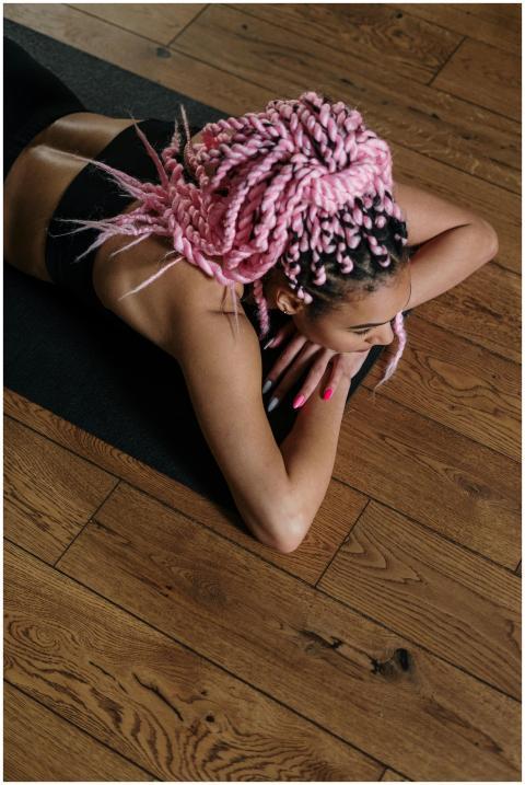 Woman with pink braids practicing yoga indoors on