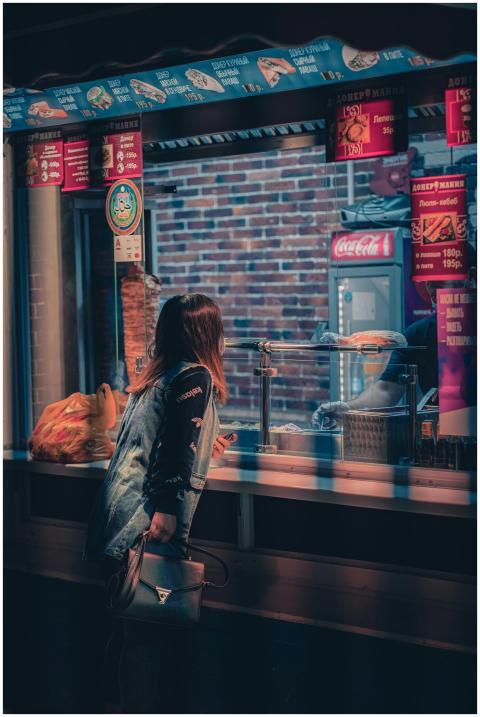 A woman orders at a street food vendor at night, c