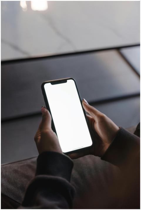 Close-up of hands holding a smartphone with a blan