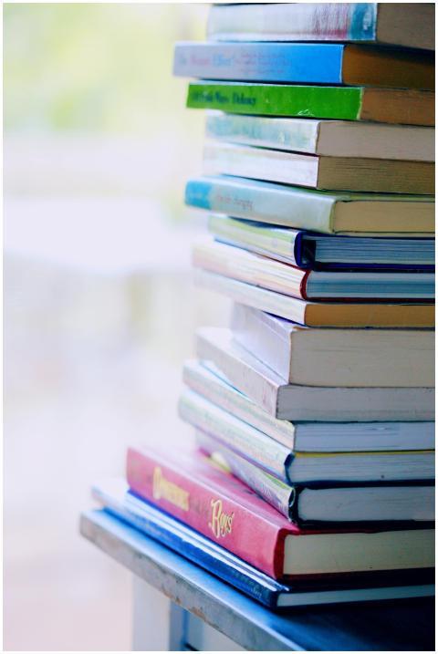 A tall stack of colorful hardcover books on a tabl