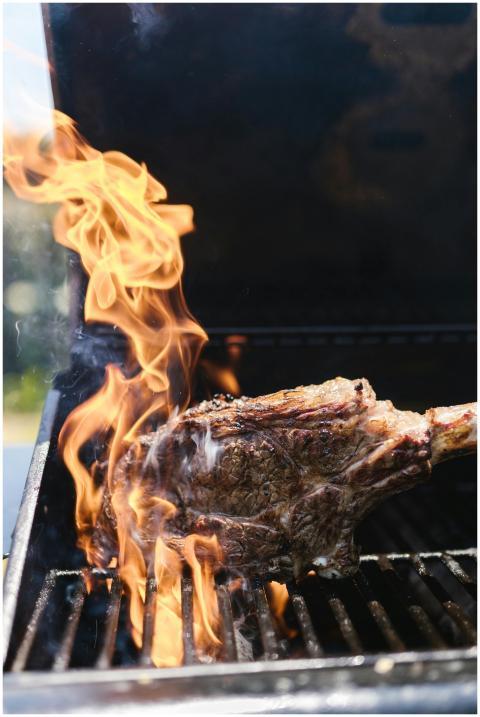 A sizzling tomahawk steak on a barbecue grill with
