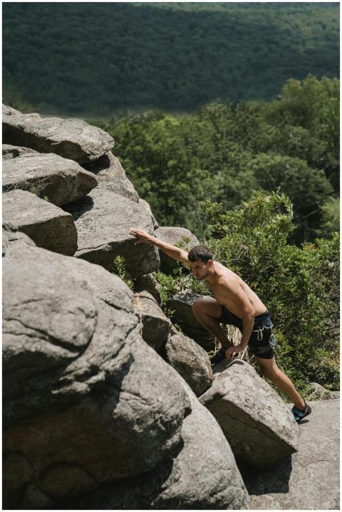 Shirtless man climbing rocky outdoor terrain showi