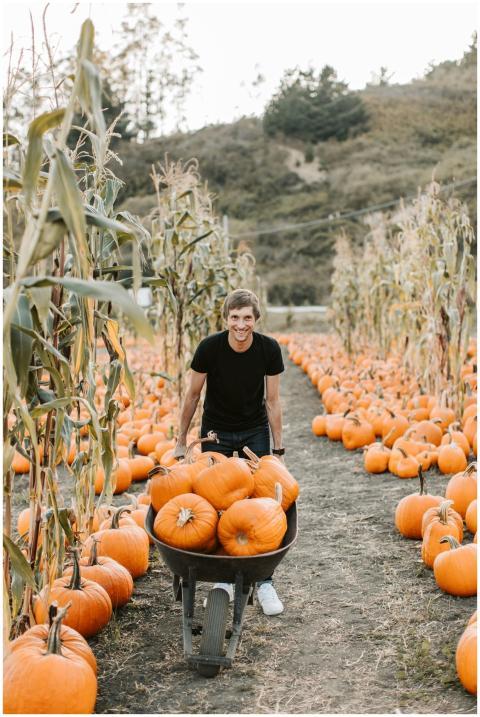 Smiling man pushing a wheelbarrow filled with pump