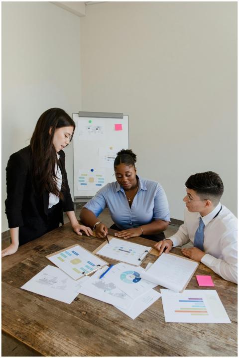 Three colleagues discuss business plans around a t