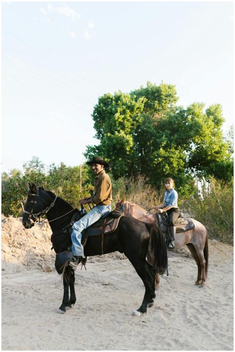 Two cowboys on horseback riding through natural te