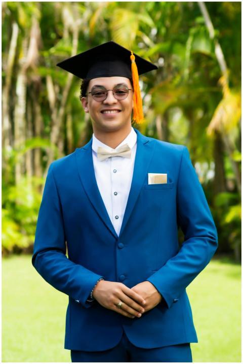 Smiling young graduate in blue suit and cap outdoo