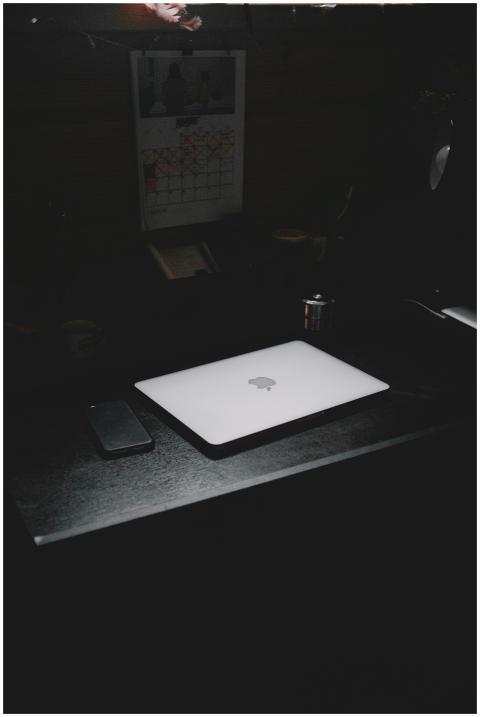 A dark, minimalist workspace featuring a laptop an
