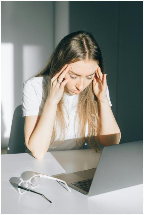 Stressed young woman with a headache working on a