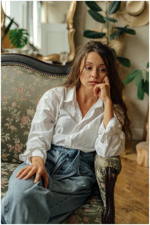 A woman in a casual outfit sits thoughtfully on a