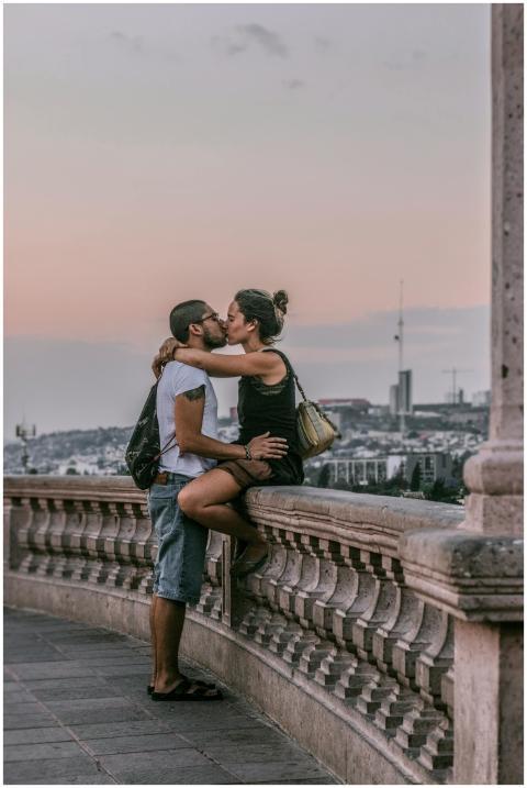A couple sharing a romantic kiss on a balcony over