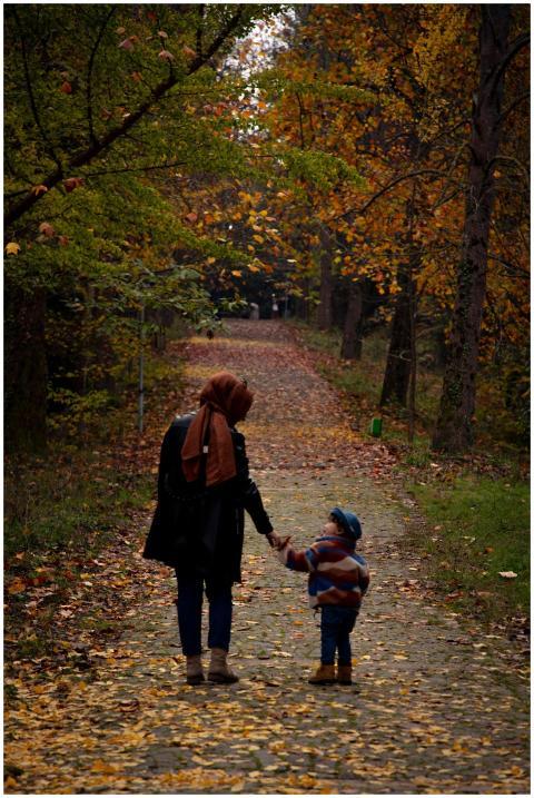 A mother and child hold hands while walking on a l