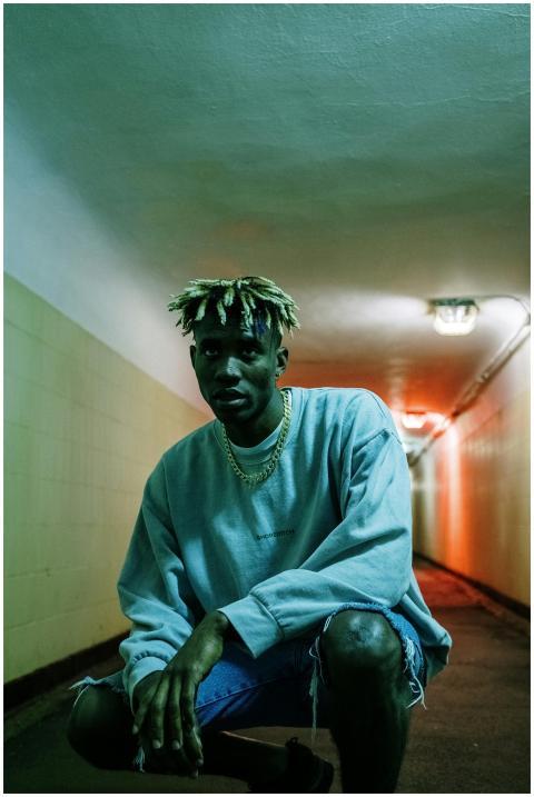 A fashionable young man poses in a neon-lit urban