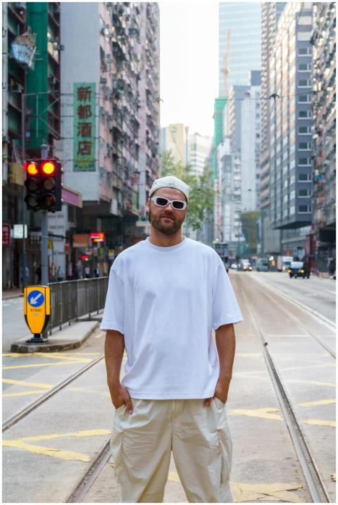 Man in casual attire stands on a city street in Ho