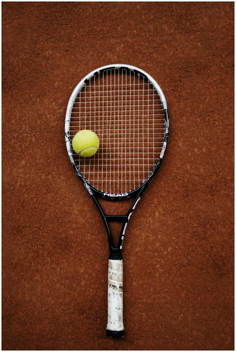 Close-up of a tennis racket and ball on a clay cou
