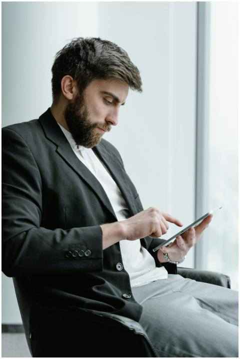 A bearded businessman in a suit jacket using a tab