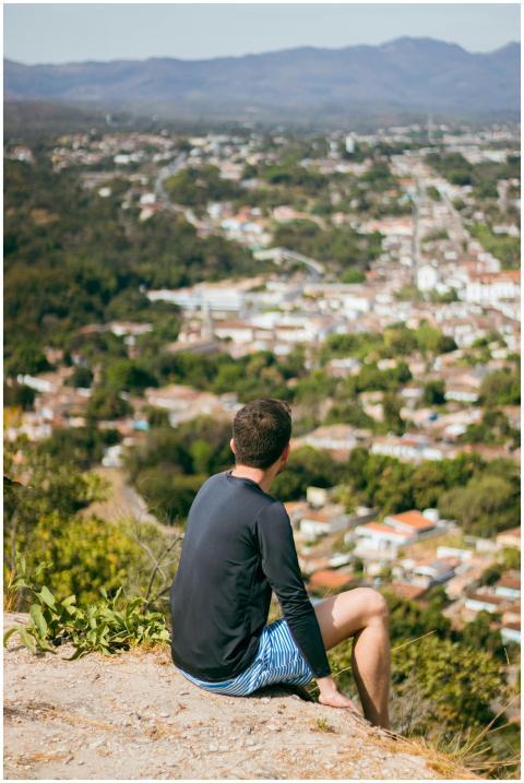 A man sitting on a hillside looks over a scenic Br