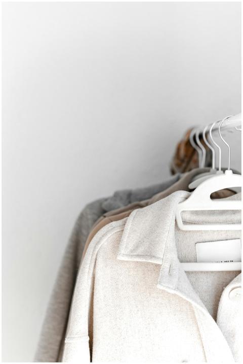 A selection of neutral-colored clothes hang neatly