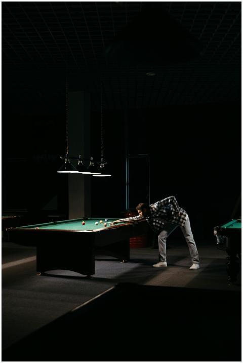 A man skillfully aiming at a billiard table under