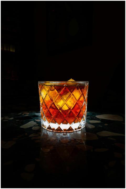 A beautifully lit whiskey cocktail in a crystal gl