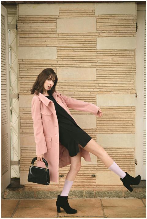 Fashion model in pink coat and black dress strikin