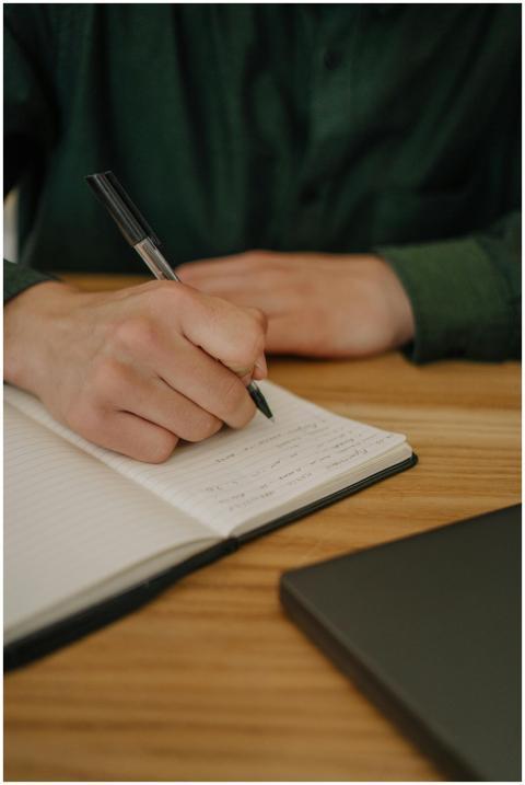 Close-up of a hand writing notes in a notebook on