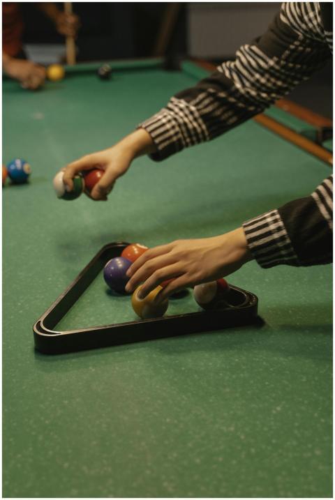 A person arranging colorful billiard balls in a ra