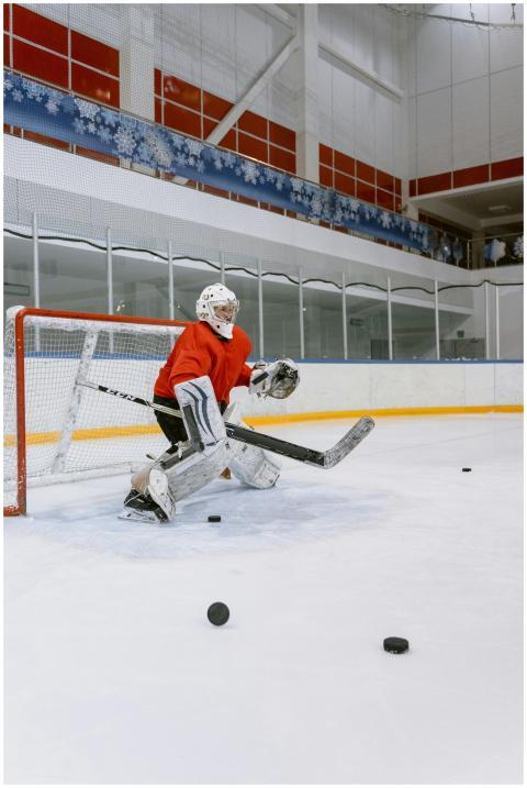 Hockey goalie in protective gear defends goal on i