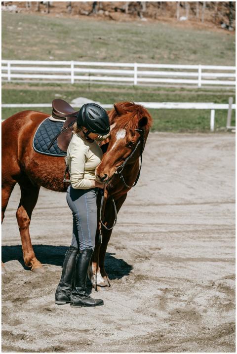 A woman in riding gear affectionately interacting