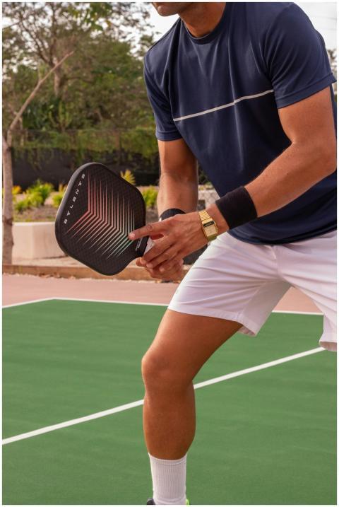 Athlete playing pickleball outdoors with paddle an