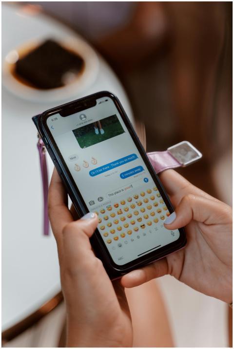 Person typing emoji in a text message on a smartph