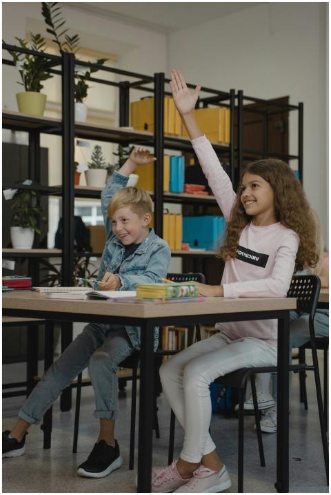 Two enthusiastic children raising hands in a moder