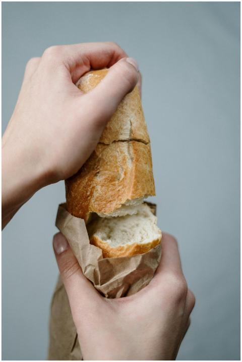 Hands breaking a piece of fresh wheat bread from a