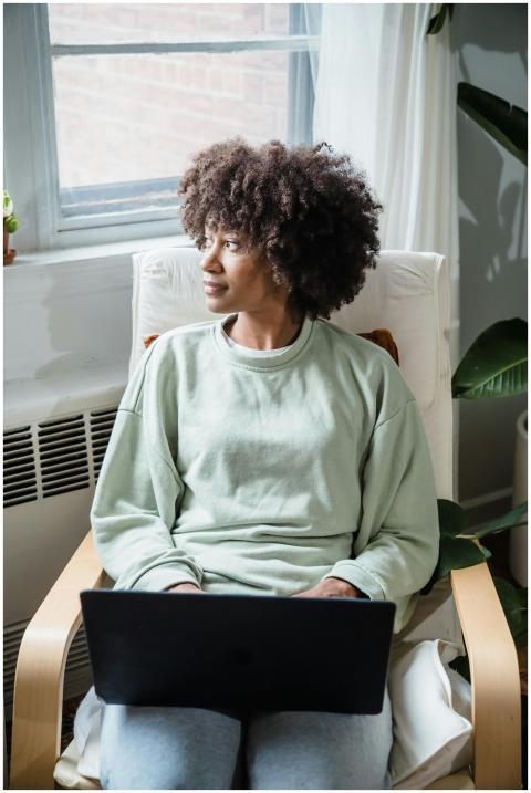 African American woman sitting in armchair using l