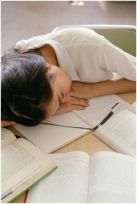 Exhausted student asleep on books illustrating aca